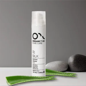 White bottle of silk potion cream moisturiser amongst aloe vera leaves