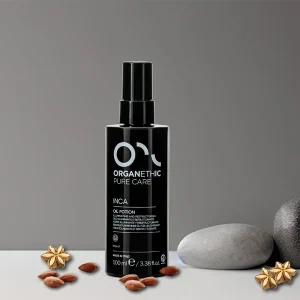 Bottle Inca Illuminating restructuring oil potion, with scattered almonds and Inca flowers.